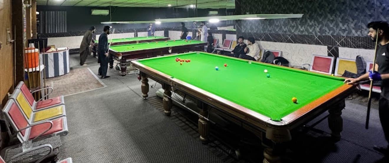 Players and green snooker tables inside the club